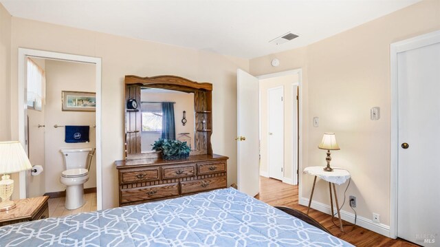 bedroom featuring hardwood / wood-style floors and ensuite bath