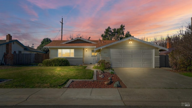 ranch-style house featuring a garage and a lawn