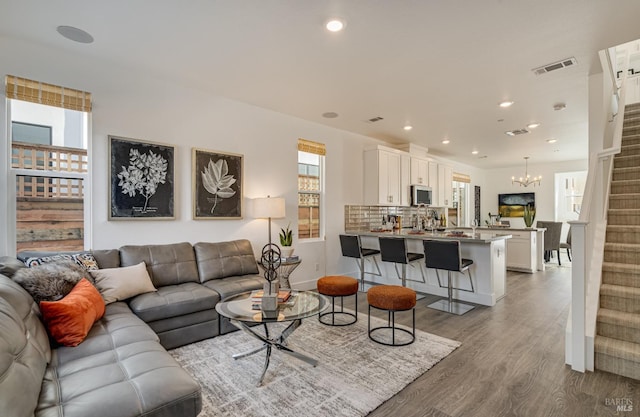 living room with plenty of natural light, an inviting chandelier, and light hardwood / wood-style flooring