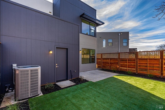 rear view of house featuring a patio, a lawn, and central air condition unit