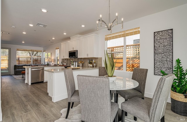 dining room with a notable chandelier, plenty of natural light, light wood-type flooring, and sink