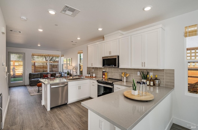 kitchen with white cabinets, sink, light wood-type flooring, kitchen peninsula, and stainless steel appliances