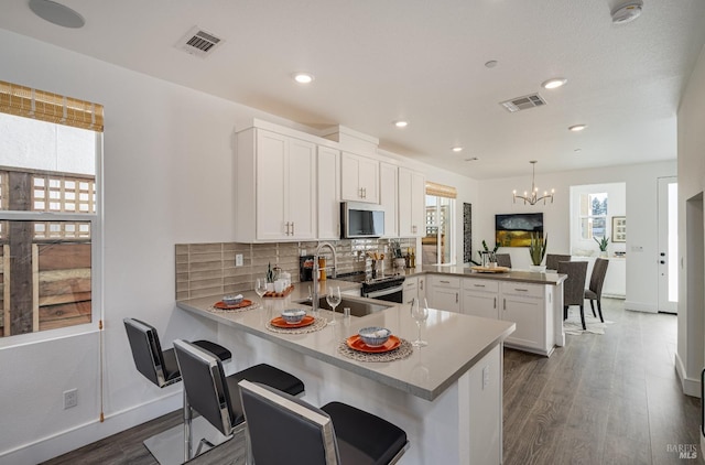 kitchen featuring kitchen peninsula, white cabinets, and pendant lighting