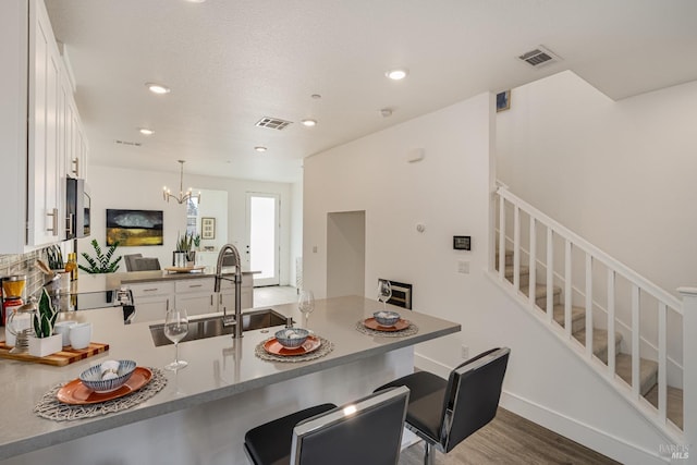 kitchen featuring pendant lighting, white cabinets, dark hardwood / wood-style flooring, kitchen peninsula, and a breakfast bar area