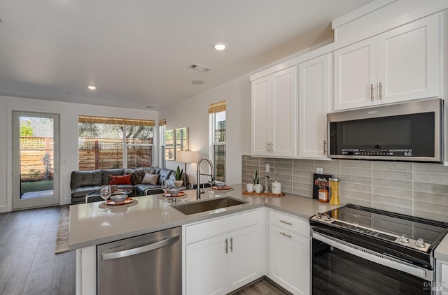 kitchen with white cabinets, kitchen peninsula, sink, and appliances with stainless steel finishes