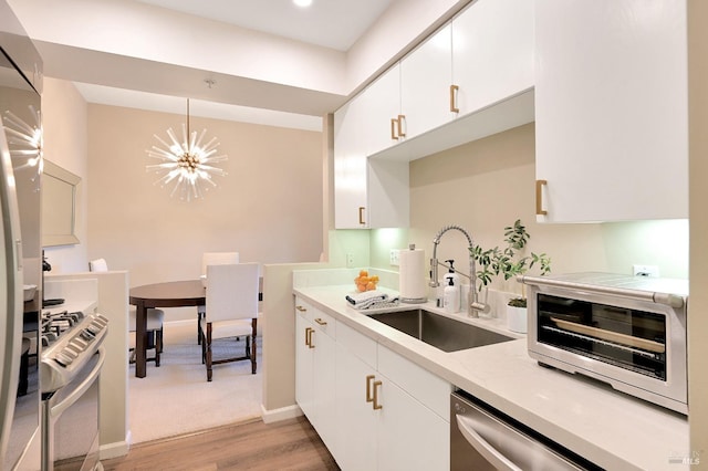 kitchen featuring decorative light fixtures, an inviting chandelier, white cabinetry, appliances with stainless steel finishes, and sink