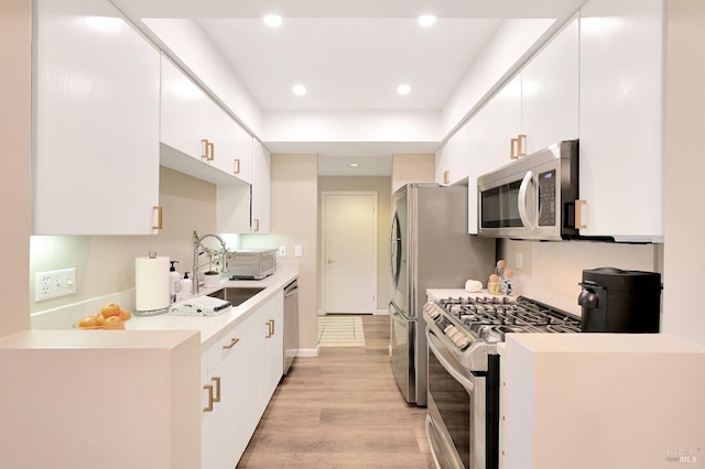 kitchen with stainless steel appliances, light wood-type flooring, white cabinets, and sink