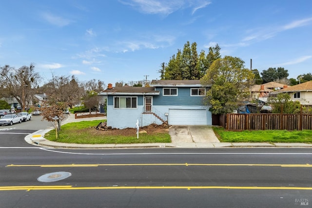 split level home featuring fence, driveway, and an attached garage