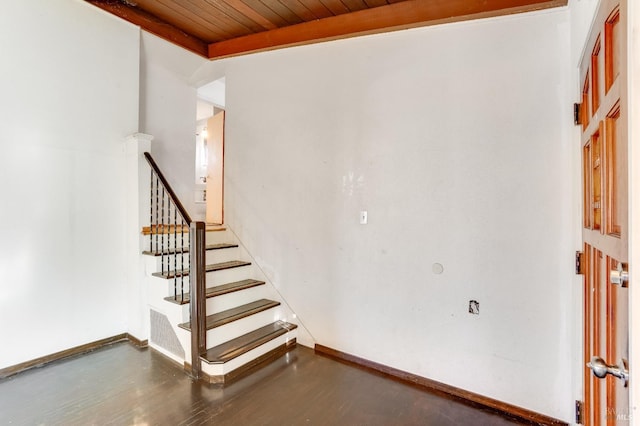 staircase featuring beam ceiling, wood ceiling, baseboards, and wood finished floors