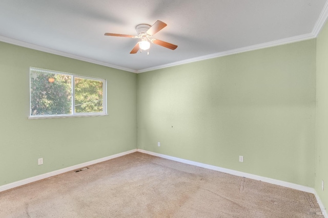 empty room with carpet floors, visible vents, ornamental molding, ceiling fan, and baseboards