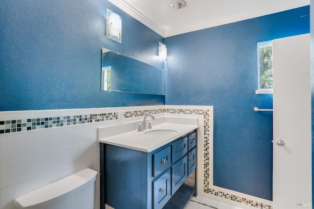 bathroom featuring a textured wall, toilet, crown molding, vanity, and tile walls