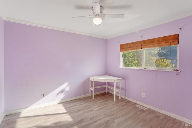 spare room with a ceiling fan, crown molding, baseboards, and wood finished floors