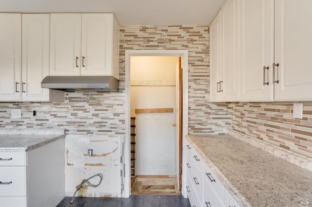 kitchen with light stone counters, decorative backsplash, white cabinets, wood finished floors, and under cabinet range hood