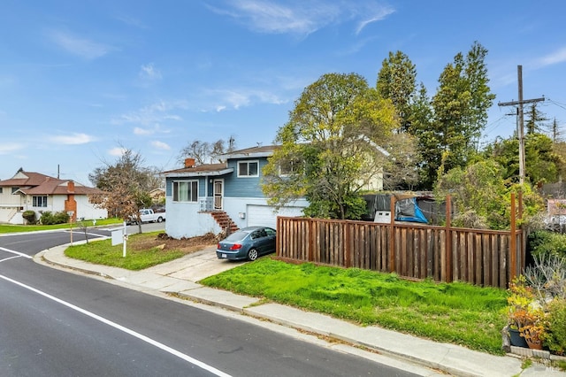 tri-level home featuring fence, driveway, and an attached garage