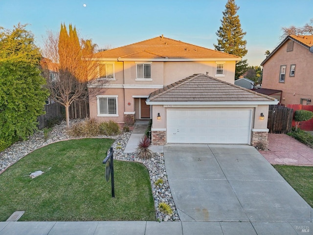 traditional home with a tile roof, an attached garage, fence, driveway, and a front lawn