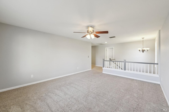 carpeted spare room with visible vents, baseboards, and ceiling fan with notable chandelier