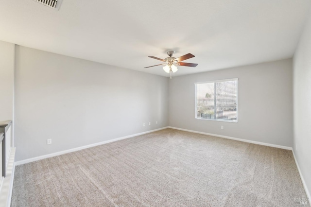 carpeted empty room featuring visible vents, a ceiling fan, and baseboards