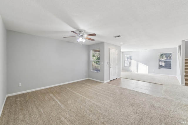 empty room with carpet, visible vents, a textured ceiling, baseboards, and stairs