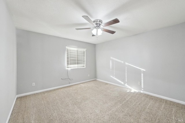 spare room with light carpet, ceiling fan, and baseboards