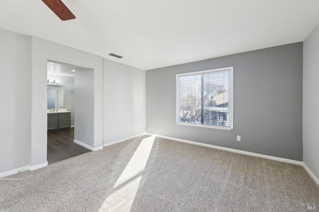 empty room featuring ceiling fan, baseboards, visible vents, and dark carpet