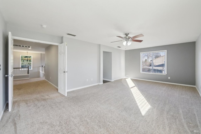 carpeted empty room with baseboards, visible vents, and a ceiling fan