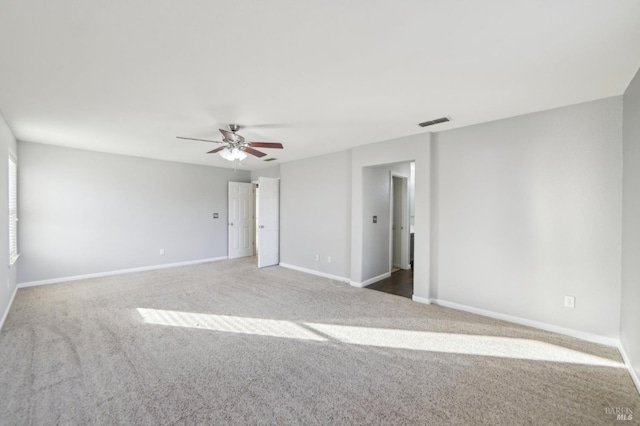 carpeted empty room featuring a ceiling fan, visible vents, and baseboards