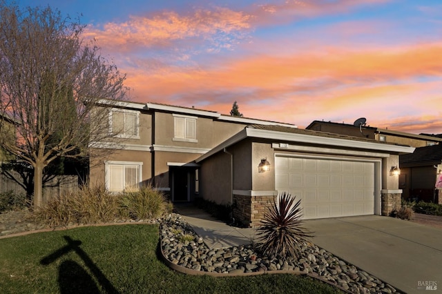 view of front facade with stone siding, an attached garage, driveway, and stucco siding