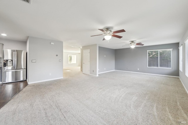 unfurnished living room with carpet floors, a ceiling fan, and baseboards