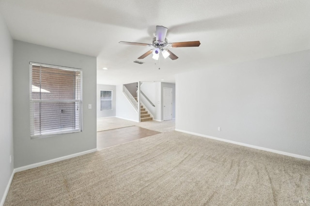 empty room featuring baseboards, visible vents, ceiling fan, stairs, and carpet flooring