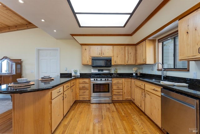 kitchen featuring kitchen peninsula, light brown cabinetry, dark stone countertops, and appliances with stainless steel finishes