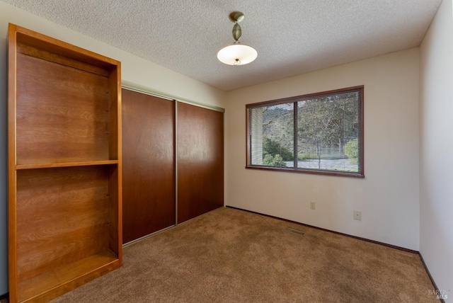 unfurnished bedroom with carpet flooring, a closet, and a textured ceiling