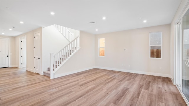 spare room featuring visible vents, baseboards, light wood-style flooring, stairway, and recessed lighting