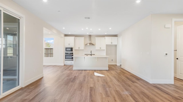 kitchen featuring oven, a sink, backsplash, built in microwave, and wall chimney exhaust hood