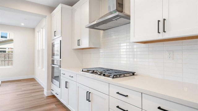 kitchen featuring wall chimney range hood, tasteful backsplash, stainless steel gas stovetop, and light countertops