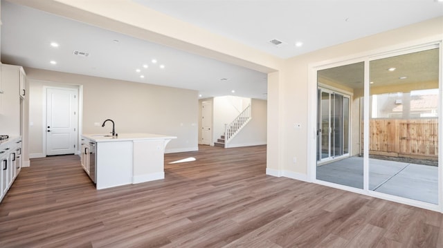 kitchen featuring white cabinets, visible vents, a sink, and wood finished floors