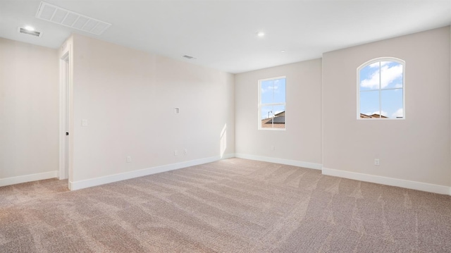 empty room featuring light colored carpet, visible vents, and baseboards