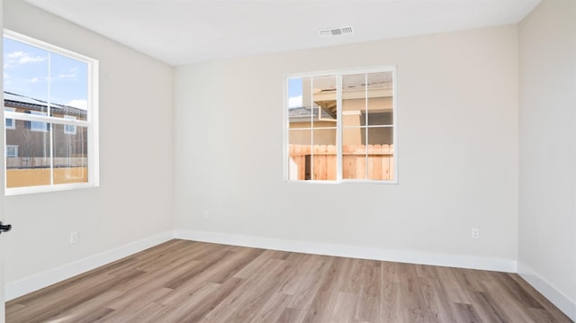 empty room featuring visible vents, baseboards, and wood finished floors