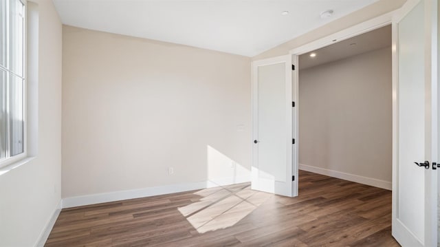 spare room featuring baseboards and wood finished floors