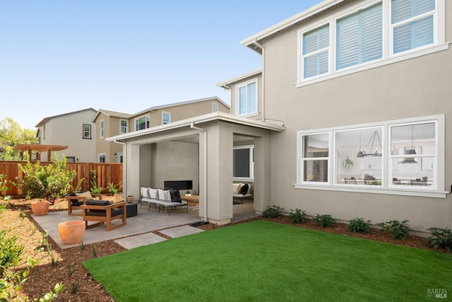 back of house with a lawn, an outdoor living space, and a patio