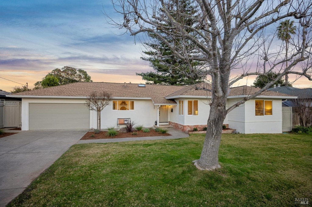 ranch-style home featuring a garage and a yard