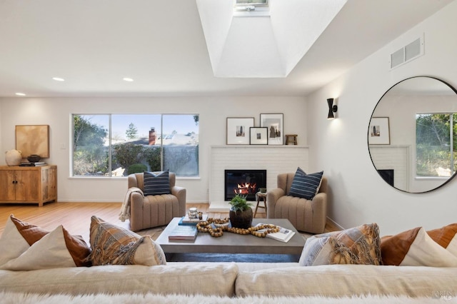 living room featuring light wood-type flooring and a brick fireplace