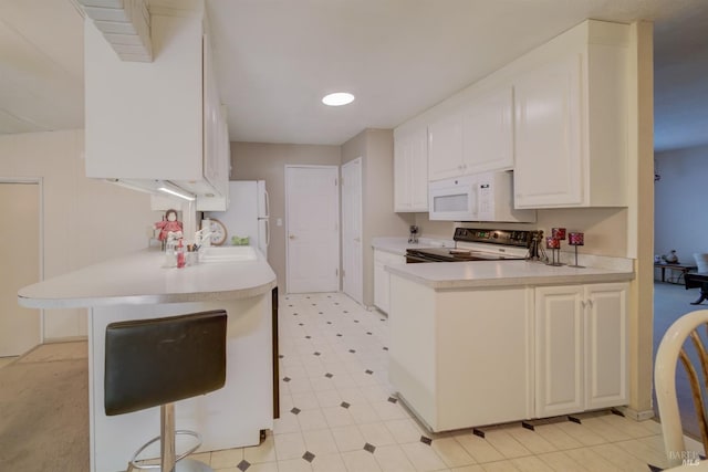 kitchen featuring kitchen peninsula, white cabinets, a breakfast bar, and white appliances