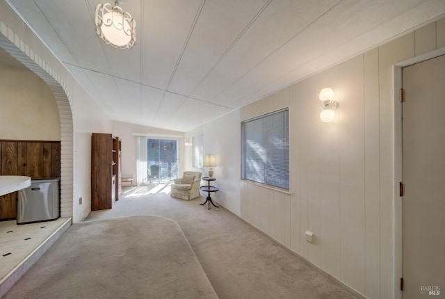 hall featuring light colored carpet and wood walls