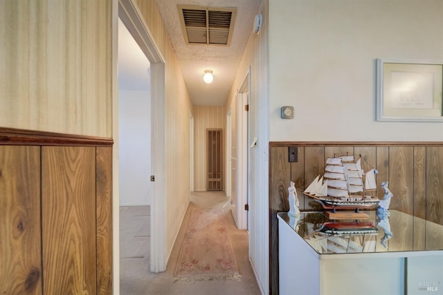 corridor featuring a textured ceiling and wooden walls