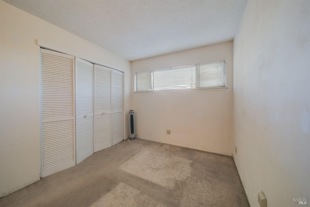 unfurnished bedroom with a textured ceiling, a closet, and light carpet