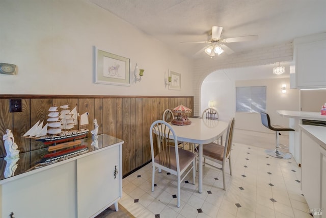 dining room with ceiling fan, wood walls, and a textured ceiling