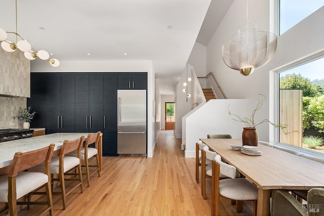 kitchen with decorative light fixtures, built in refrigerator, tasteful backsplash, light hardwood / wood-style floors, and range