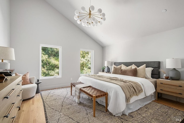 bedroom featuring high vaulted ceiling, light wood-type flooring, and a notable chandelier