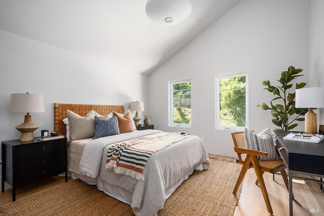 bedroom with light hardwood / wood-style flooring and high vaulted ceiling