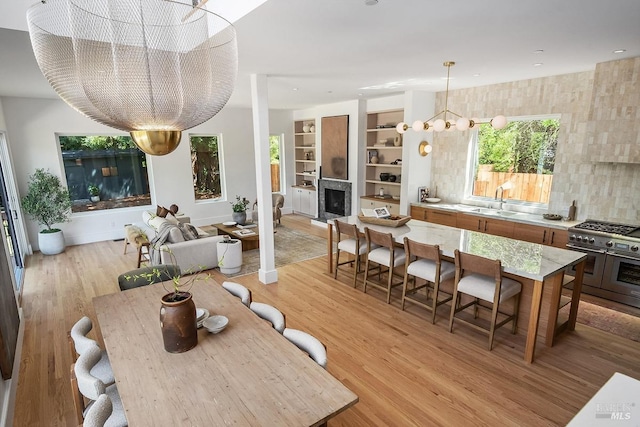 dining room featuring light wood-type flooring, built in features, a chandelier, and sink